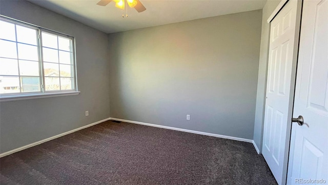 unfurnished bedroom featuring dark carpet, baseboards, and a closet