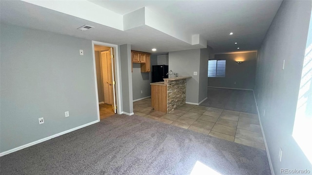 unfurnished living room featuring baseboards, light tile patterned floors, and light carpet