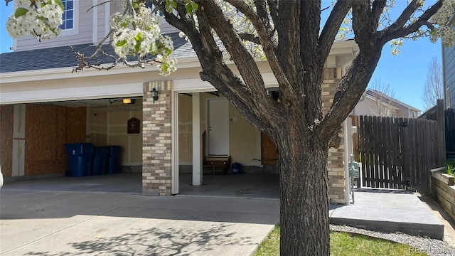 exterior space with a garage, roof with shingles, fence, and driveway