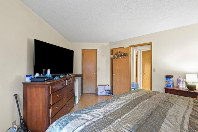 bedroom with light wood-type flooring and a textured ceiling