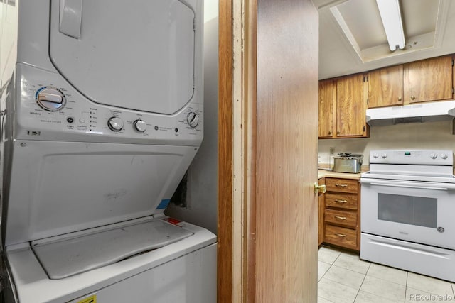 clothes washing area with stacked washer / drying machine, laundry area, and light tile patterned floors