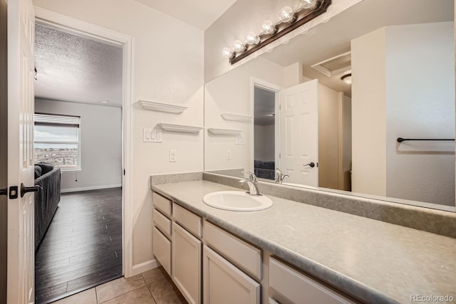 bathroom with a textured ceiling, tile patterned floors, and vanity