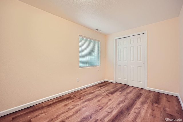 unfurnished bedroom with a closet, hardwood / wood-style floors, and a textured ceiling