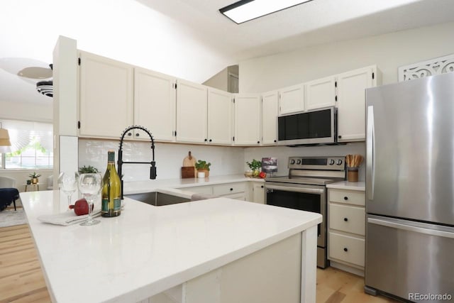 4302 Nepal St, Denver, CO 80249 - kitchen featuring appliances with stainless steel finishes, a sink, a peninsula, light wood-style flooring, and light countertops