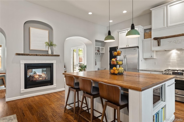 4425 Irving St, Denver, CO 80211 - kitchen with stainless steel appliances, wood counters, arched walkways, white cabinets, and recessed lighting