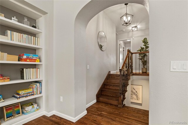 4425 Irving St, Denver, CO 80211 - staircase featuring wood finished floors, arched walkways, a chandelier, baseboards, and built in shelves