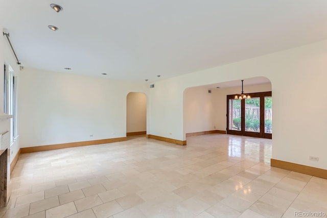 tiled empty room featuring french doors and a notable chandelier