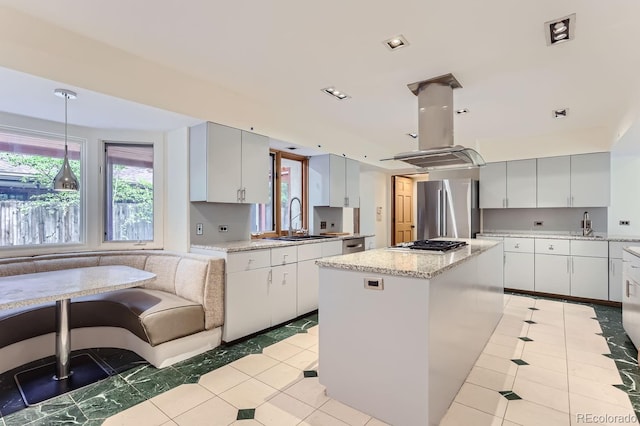 kitchen featuring island range hood, stainless steel appliances, a center island, pendant lighting, and sink