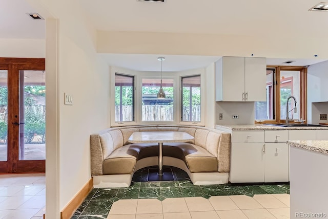 kitchen featuring hanging light fixtures, white cabinets, french doors, and sink