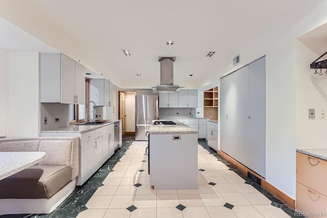 kitchen with island range hood, stainless steel appliances, a kitchen island, a breakfast bar, and sink