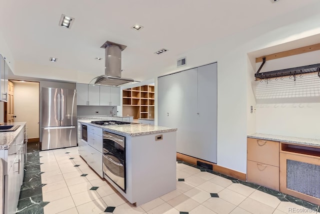 kitchen featuring white cabinets, a kitchen island, island exhaust hood, stainless steel appliances, and light stone counters