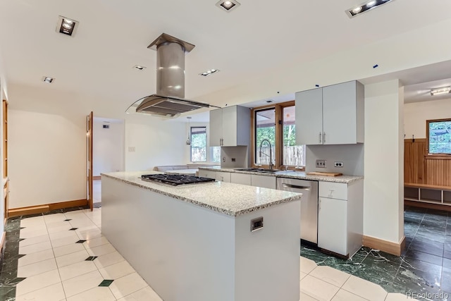 kitchen with light stone countertops, appliances with stainless steel finishes, a center island, island exhaust hood, and sink