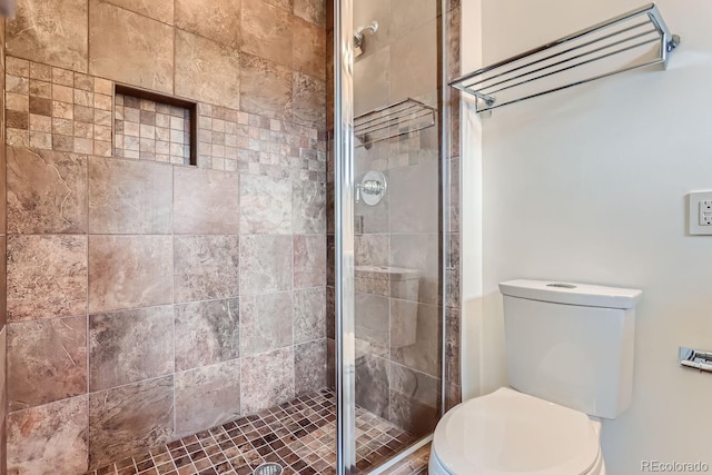 bathroom with a shower with shower door and toilet