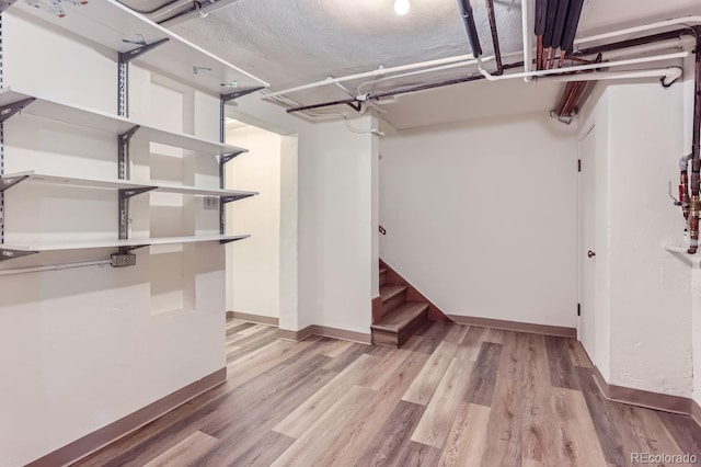 basement featuring a textured ceiling and light hardwood / wood-style floors