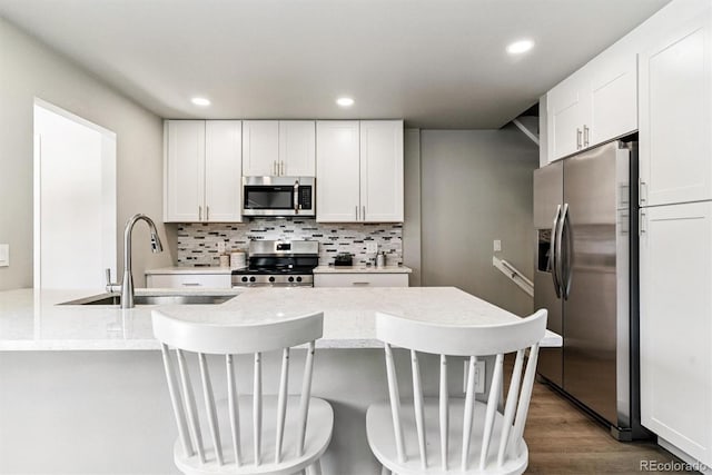 1927 S Peoria St, Aurora, CO 80014 - kitchen with appliances with stainless steel finishes, tasteful backsplash, white cabinetry, wood finished floors, and recessed lighting