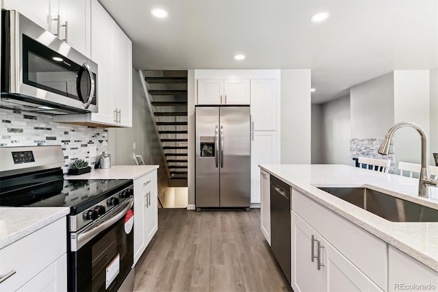 1927 S Peoria St, Aurora, CO 80014 - kitchen with appliances with stainless steel finishes, decorative backsplash, recessed lighting, light wood-style flooring, and white cabinetry