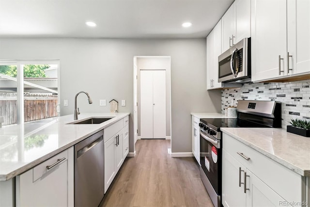 1927 S Peoria St, Aurora, CO 80014 - kitchen with appliances with stainless steel finishes, tasteful backsplash, light wood-type flooring, recessed lighting, and white cabinets