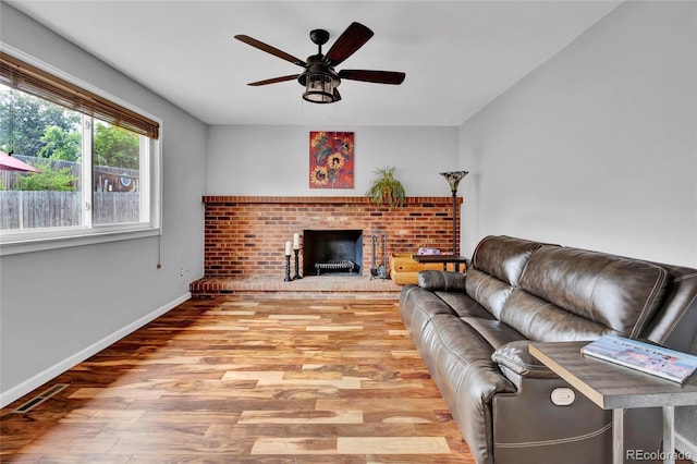 13624 Omega Cir, Lone Tree, CO 80124 - living room featuring a ceiling fan, light wood-type flooring, a brick fireplace, and baseboards