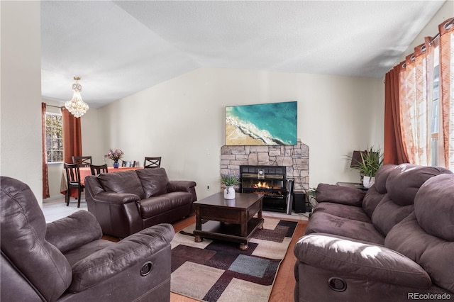 living room featuring a fireplace, lofted ceiling, and an inviting chandelier