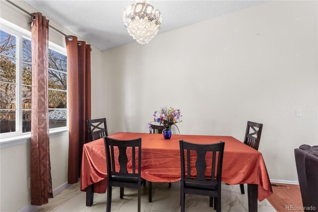 dining area with plenty of natural light, a textured ceiling, and a notable chandelier