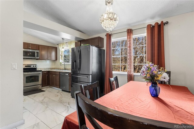 kitchen featuring decorative backsplash, stainless steel appliances, sink, hanging light fixtures, and lofted ceiling