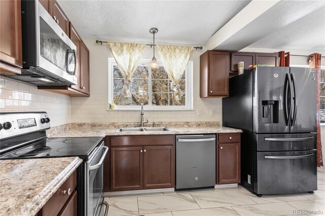 kitchen featuring hanging light fixtures, sink, decorative backsplash, a textured ceiling, and appliances with stainless steel finishes