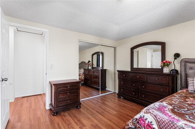 bedroom with a textured ceiling, hardwood / wood-style flooring, and a closet