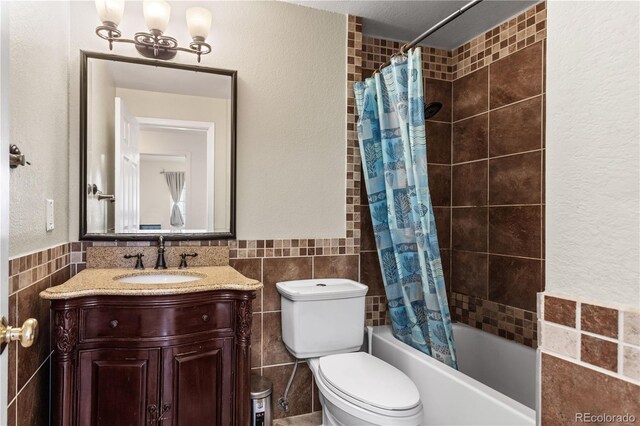 full bathroom with shower / bath combination with curtain, vanity, an inviting chandelier, tile walls, and toilet