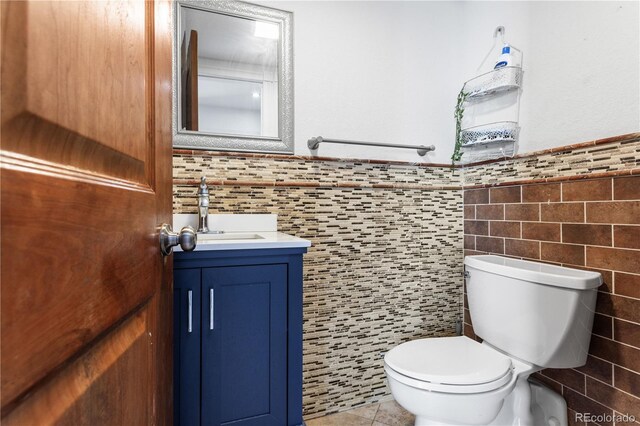 bathroom featuring tile patterned flooring, vanity, toilet, and tile walls