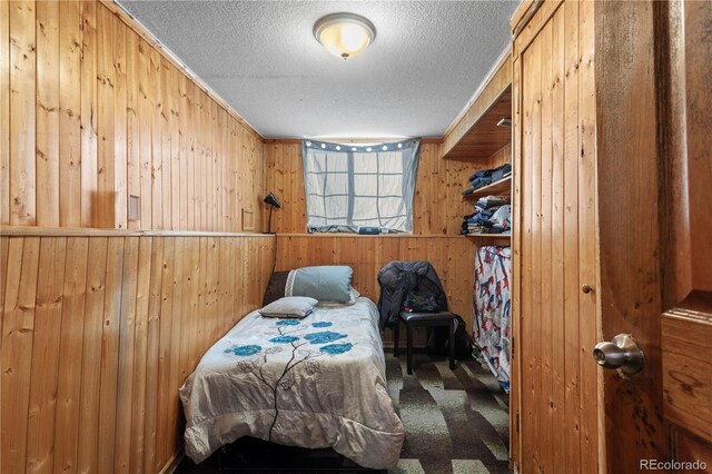 carpeted bedroom featuring wood walls and a textured ceiling