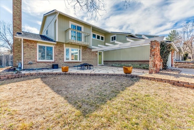 rear view of house featuring a patio, brick siding, and a chimney