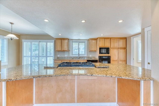 kitchen featuring black appliances, light stone counters, light brown cabinets, and a textured ceiling