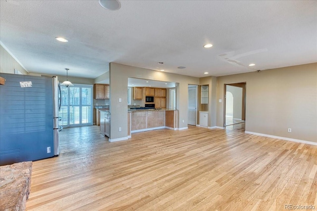 unfurnished living room featuring baseboards, light wood-style floors, and a textured ceiling