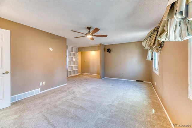 carpeted empty room with baseboards, visible vents, a textured ceiling, and ceiling fan