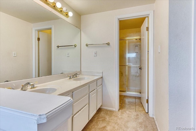 bathroom with double vanity, a stall shower, baseboards, and a sink