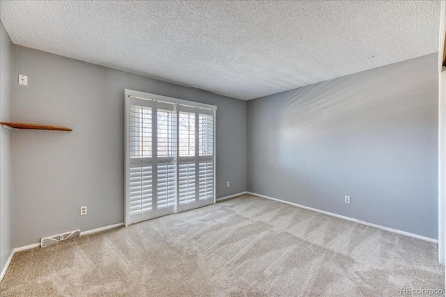 carpeted spare room with baseboards, visible vents, and a textured ceiling