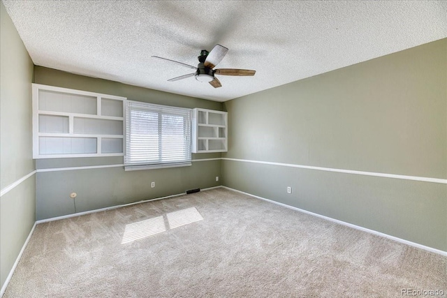 empty room with carpet, a ceiling fan, baseboards, and a textured ceiling