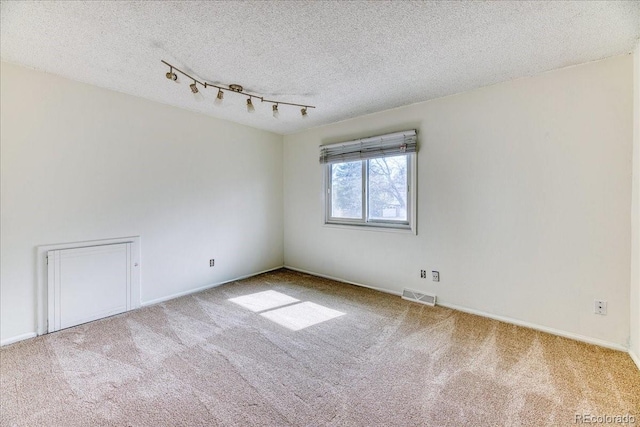 empty room featuring visible vents, a textured ceiling, and carpet