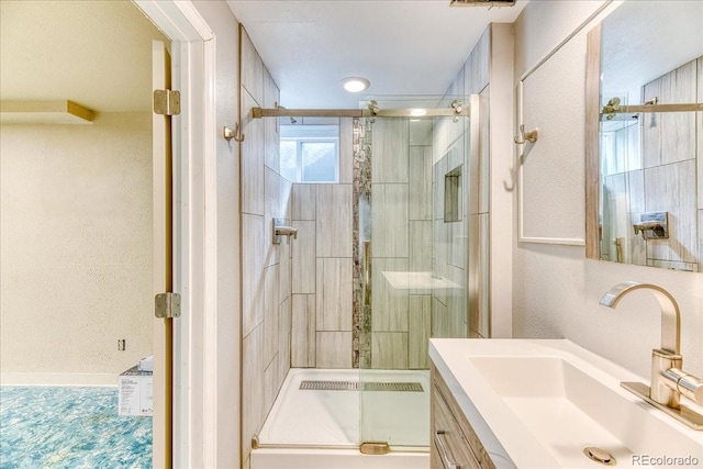 full bathroom with vanity, a shower stall, and a textured wall