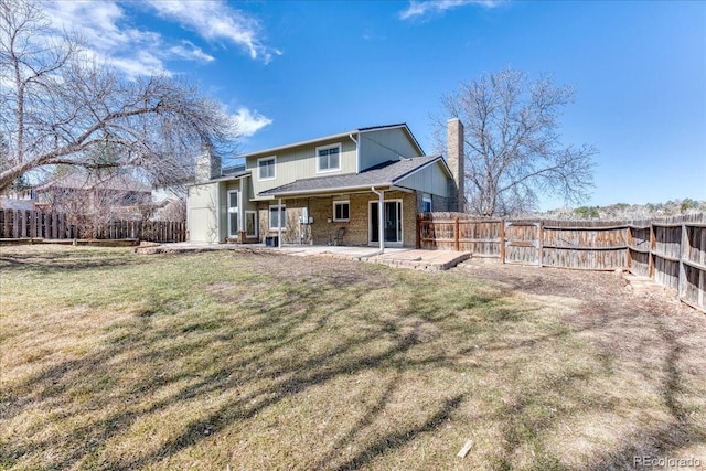 rear view of house with a lawn, a patio, a fenced backyard, brick siding, and a chimney