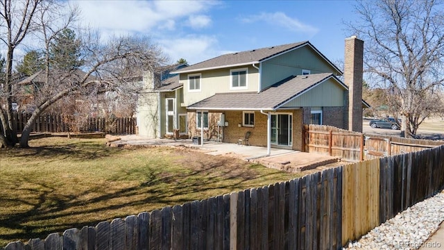 rear view of house with a patio, a fenced backyard, a chimney, a lawn, and brick siding