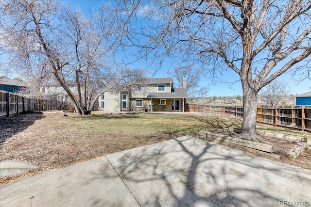 back of property with a yard, a fenced backyard, and a chimney