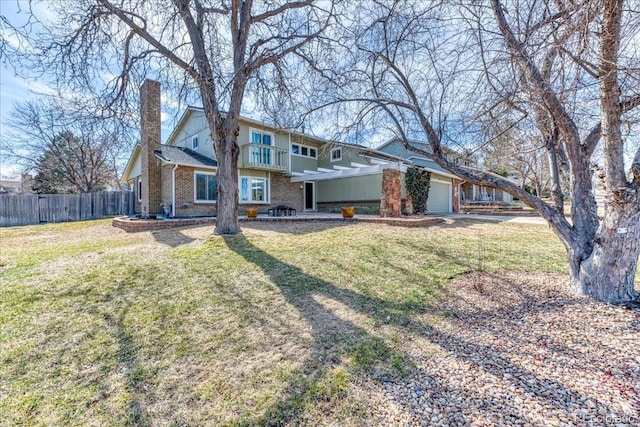 view of front of property featuring fence, a front yard, a garage, brick siding, and a chimney