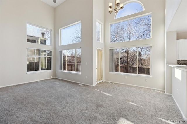 unfurnished living room with baseboards, carpet, and a notable chandelier