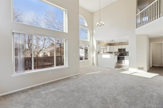 unfurnished living room with light carpet, baseboards, a chandelier, and a healthy amount of sunlight