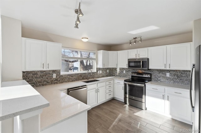 kitchen featuring appliances with stainless steel finishes, white cabinets, a sink, and backsplash