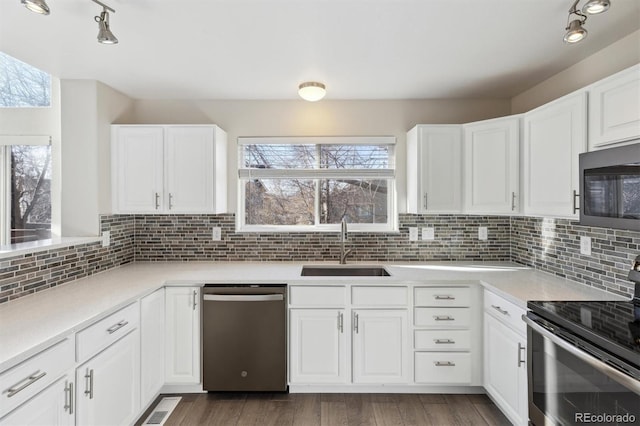 kitchen featuring appliances with stainless steel finishes, backsplash, a sink, and white cabinetry