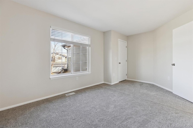 carpeted empty room featuring baseboards and visible vents