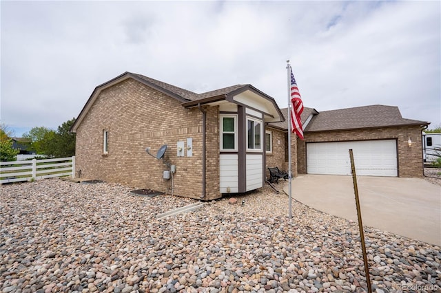 view of home's exterior featuring brick siding, driveway, and roof with shingles