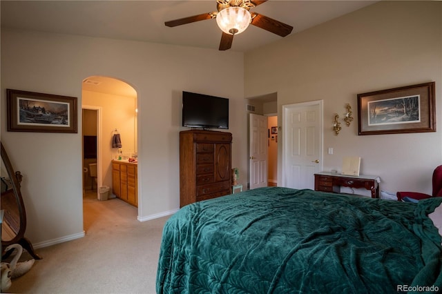 bedroom featuring arched walkways, light colored carpet, lofted ceiling, baseboards, and ensuite bath
